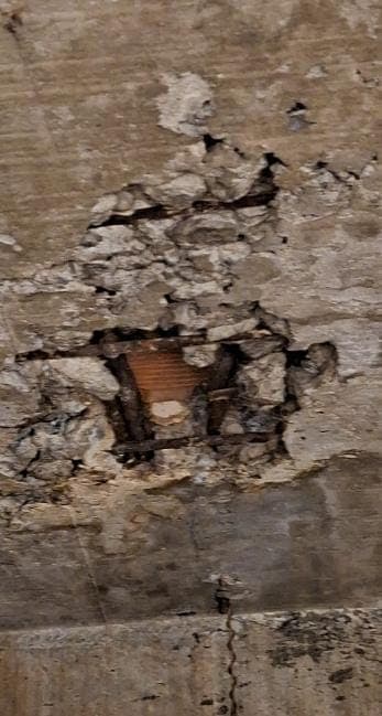 Desplacamento localizado de concreto em viga, com estribo e armadura longitudinal expostos